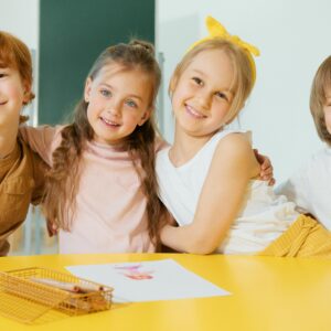 Happy group of children smiling and posing together in a bright classroom setting.